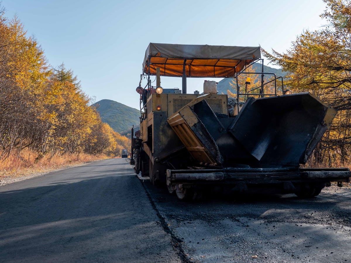 Paving machine laying fresh asphalt on a driveway approach